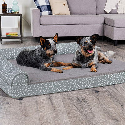 Two black and gray dogs lying on a teal and gray FurHaven brand dog bed 